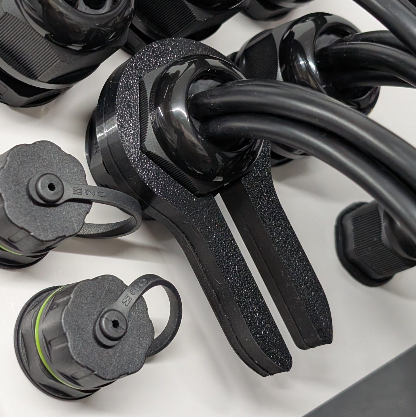 Close up view of black 33mm cable gland passthrough tool of enclosure with wire protruding.