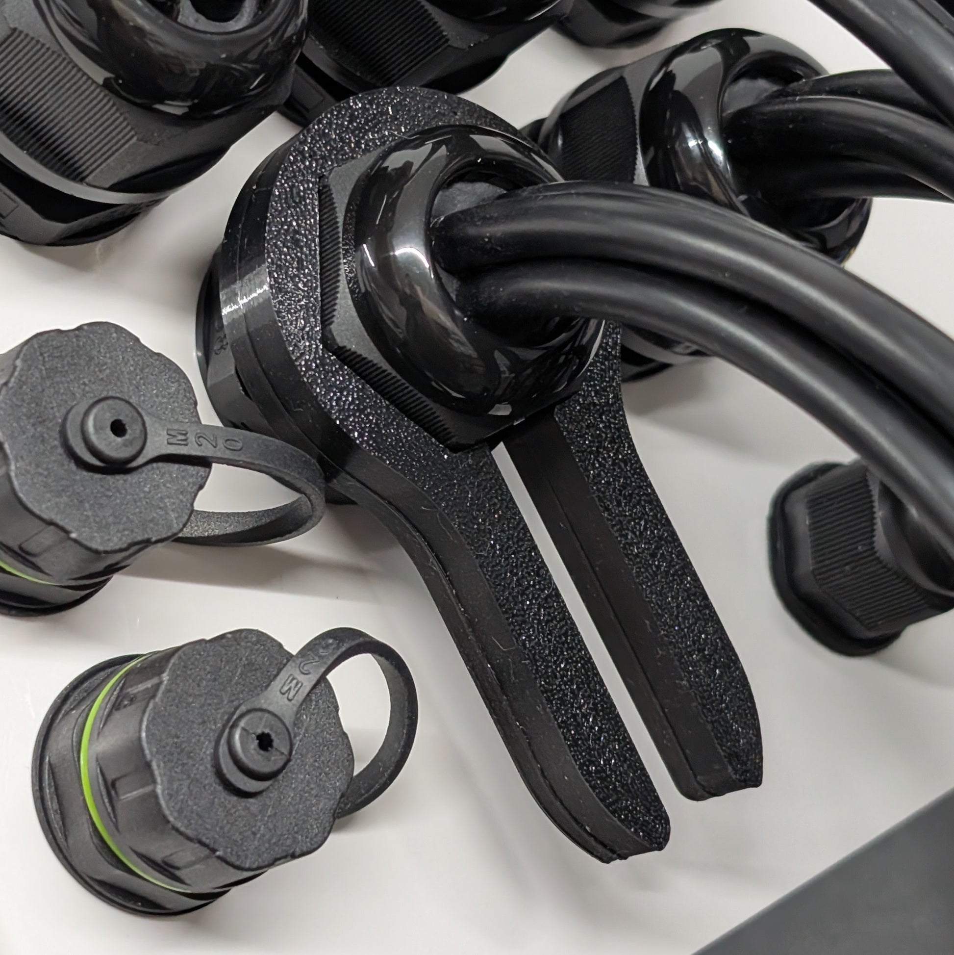 Close up view of black 33mm cable gland passthrough tool of enclosure with wire protruding.