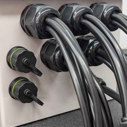 Close-up of 4-hole glands and ethernet passthrough connectors installed in grey plastic enclosure.