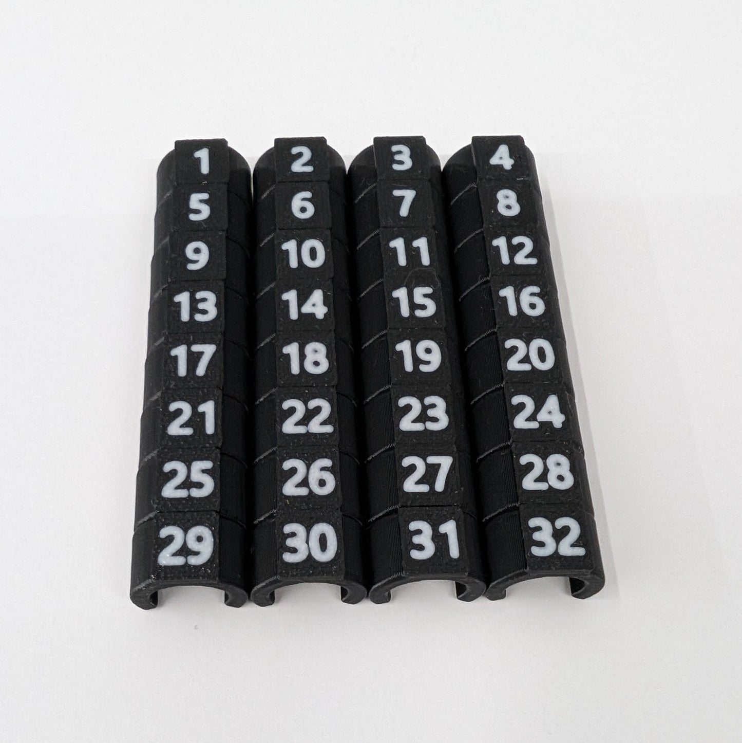 Close-up of black cable ID clips with white numbers 1-32 on a white background