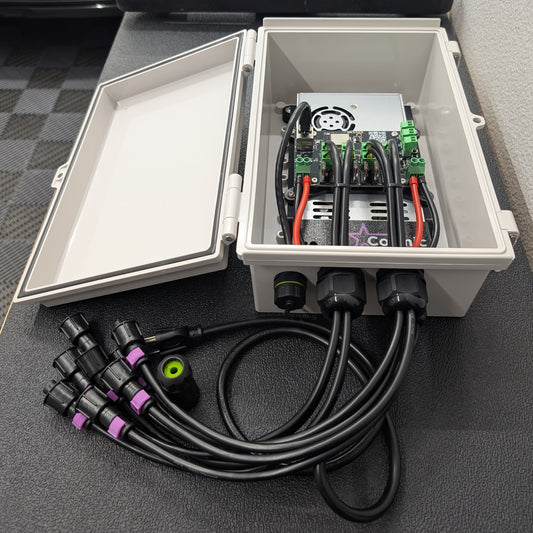 Cosmic 8-Series Controller with enclosure lid opening showing Baldrick8 boards and Mean Well power supply, on black workbench top.