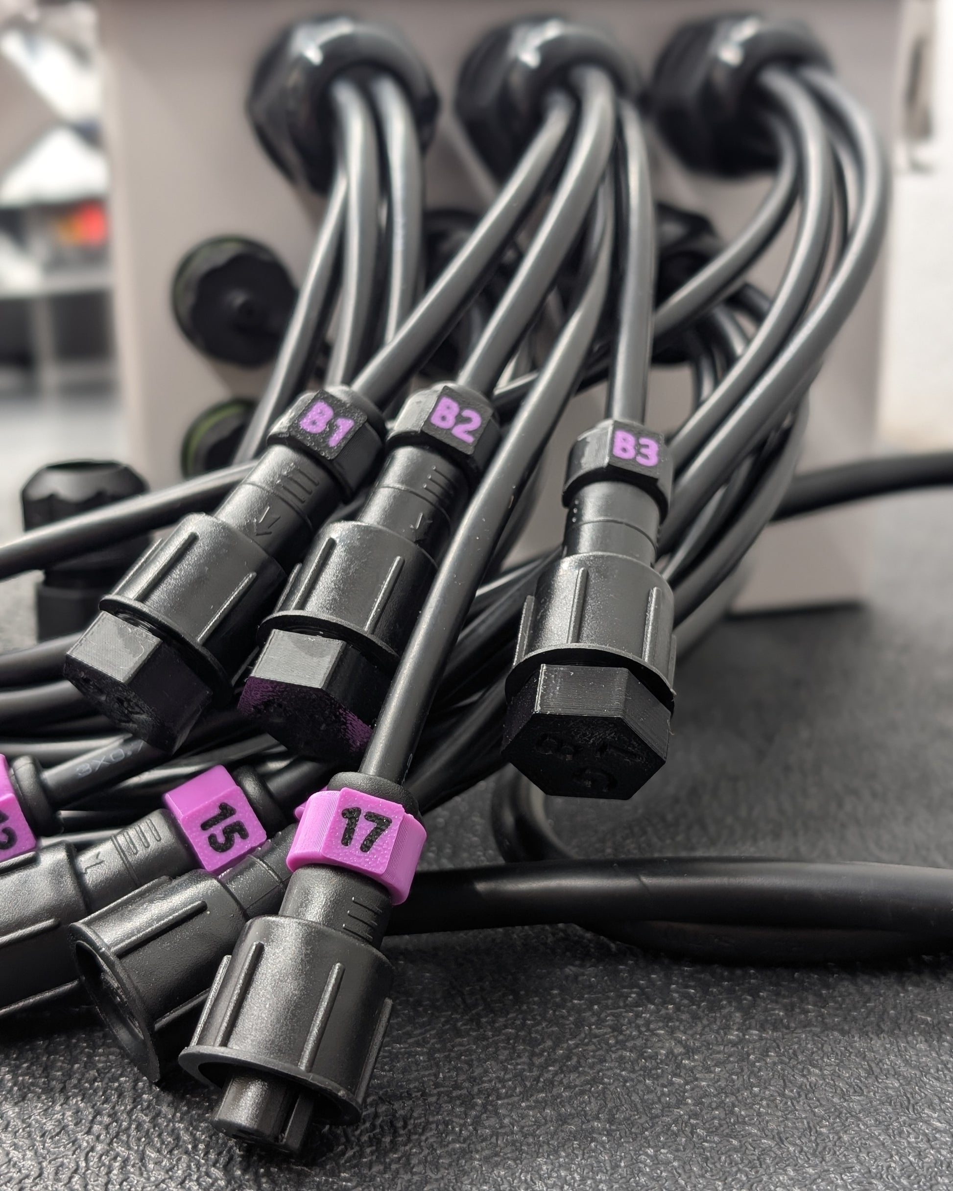 Close up image of black wiring with burple ID tags coming out of Cosmic Pro-Series weatherproof enclosure.
