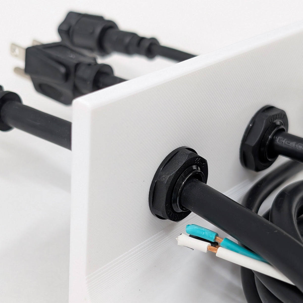 Back side view of M16L long-thread cable glands installed through a thick panel with xConnect, 16/3 SJTW, and 14/3 SJTW cables