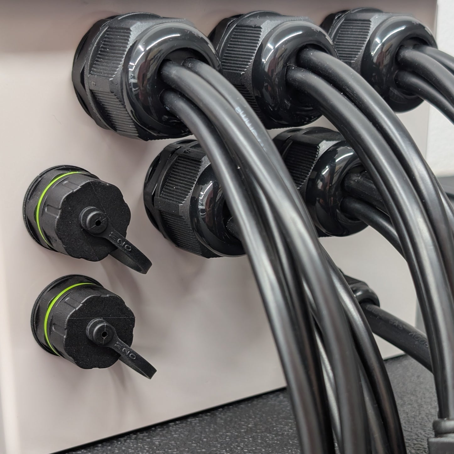 Close-up of 4-hole glands and ethernet passthrough connectors installed in grey plastic enclosure.