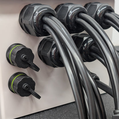 Close-up of 4-hole glands and ethernet passthrough connectors installed in grey plastic enclosure.