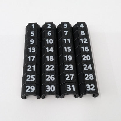 Close-up of black cable ID clips with white numbers 1-32 on a white background