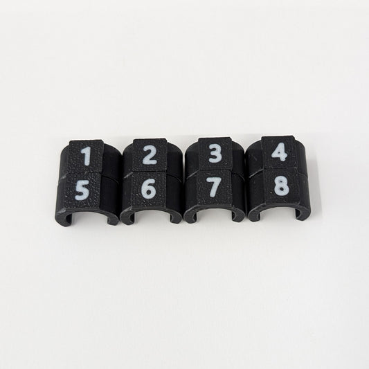 Close-up of black cable ID clips with white numbers 1-8 on a white background
