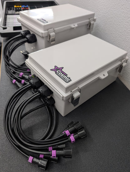 Two Cosmic Controllers gray waterproof plastic pixel controller enclosures with black electrical cables coming out of them.